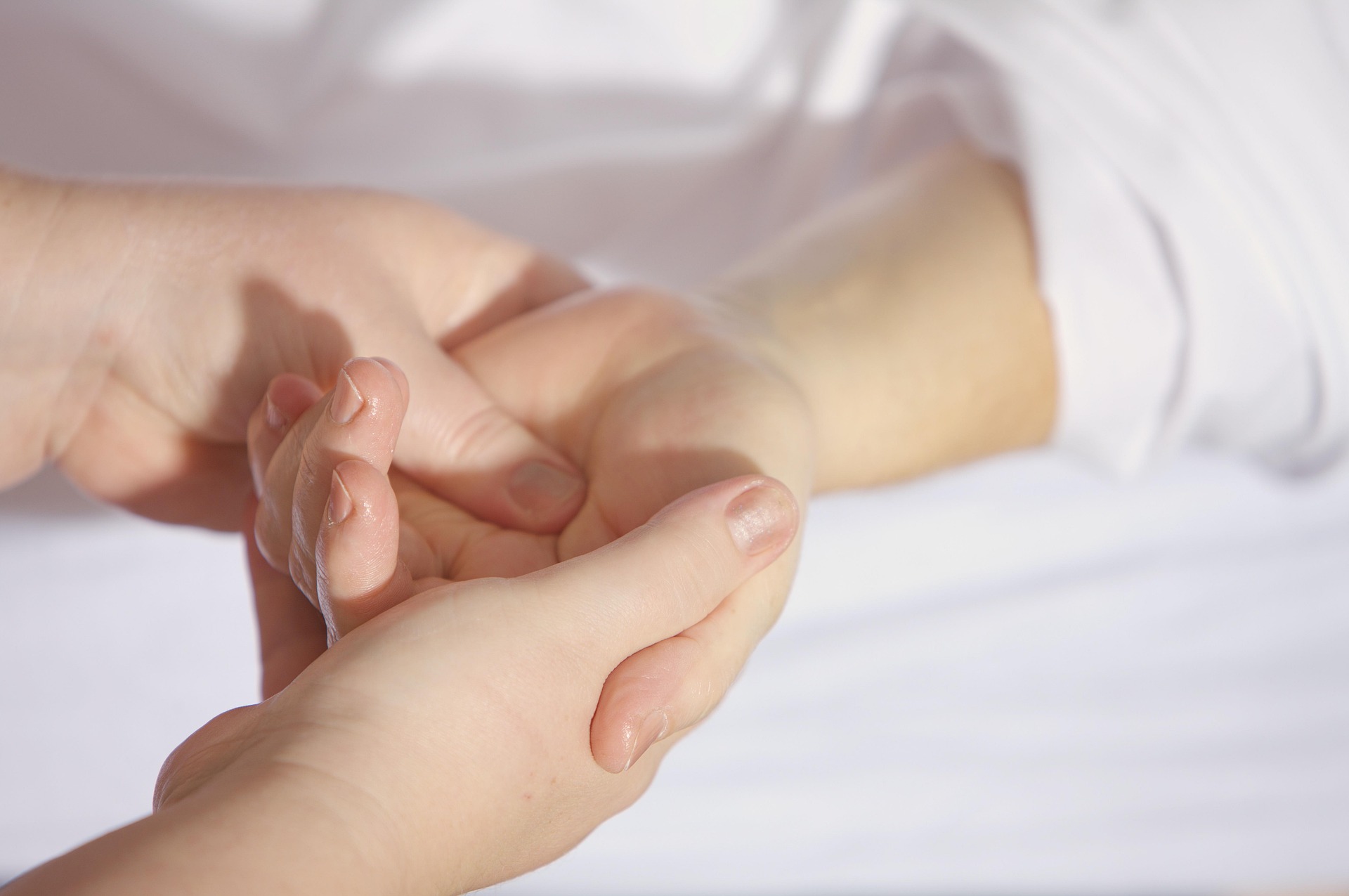 Therapeutin behandelt behutsam die Hand einer Patientin zur Förderung der Feinmotorik